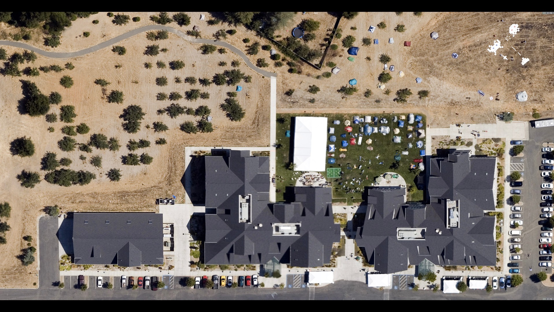 Sky view shot of Foo Camp, where buildings and tents can be seen.